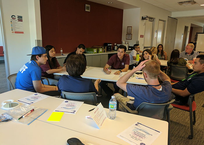 A group of diverse individuals seated around a table discussing inclusive recreation.