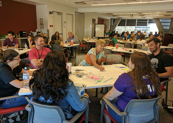 A group of diverse individuals seated around a table discussing inclusive recreation.