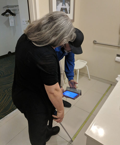 Two Life Quest team members measuring room dimensions