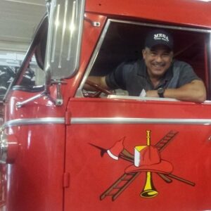 Tony Del Rio sitting in the driver's seat of a fire engine.