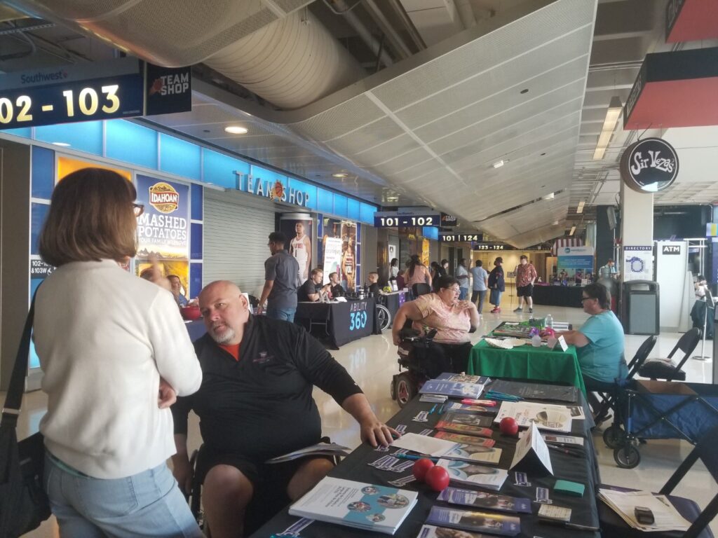 Disability Summit event that includes several booths and individuals with various disabilities chatting.