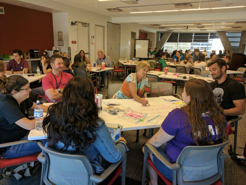 Training class with employees doing activities at multiple tables.