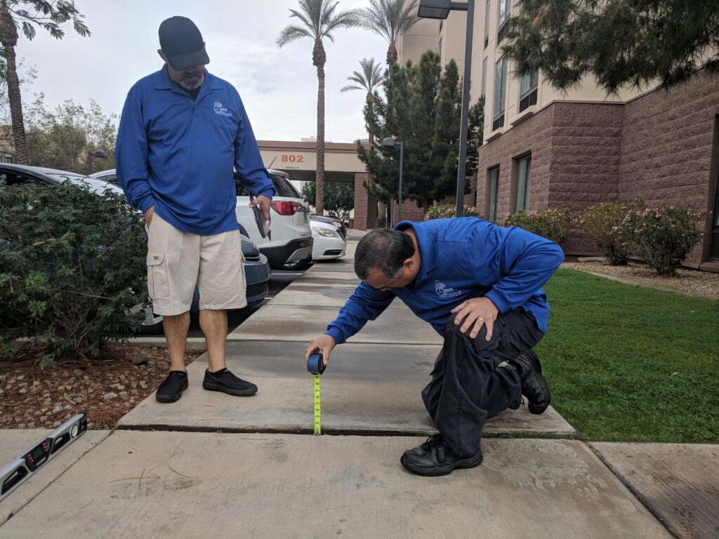 Two Life Quest team members measuring a change in level on a sidewalk.