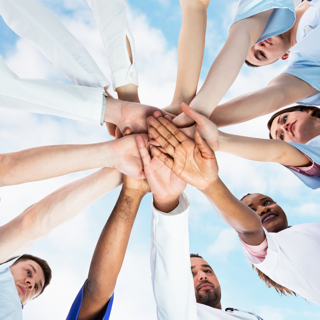 A group of diverse individuals standing in a circle, stacking their hands together—commonly referred to as a "break."