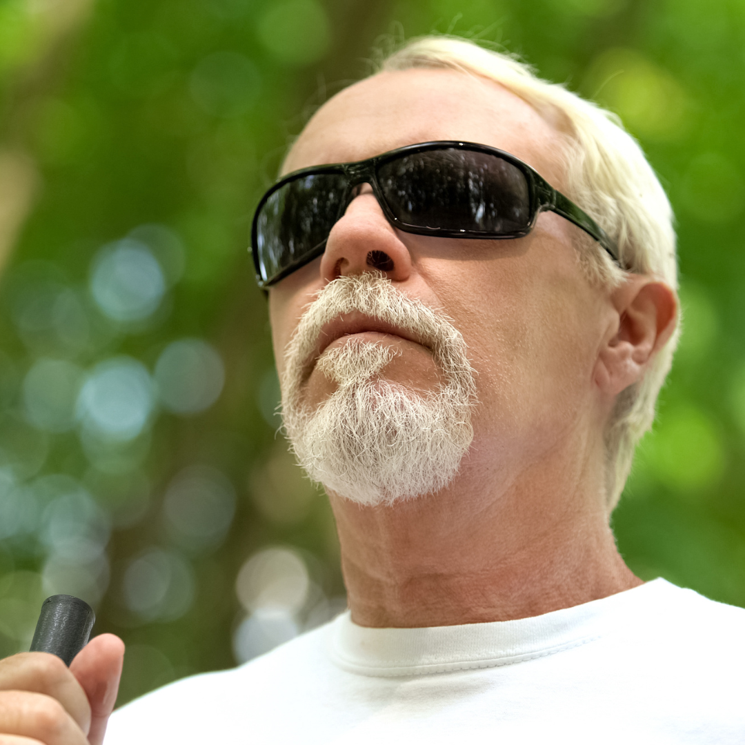 A blind man with a white beard wearing sunglasses.